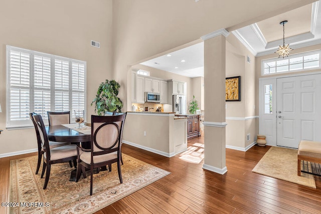 dining room featuring ornate columns, crown molding, a towering ceiling, and dark hardwood / wood-style floors