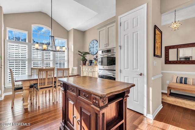 kitchen featuring vaulted ceiling, hardwood / wood-style flooring, decorative light fixtures, and a center island