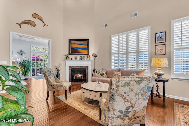 living room featuring a high end fireplace, dark wood-type flooring, and a healthy amount of sunlight