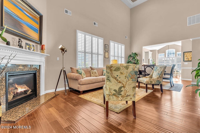 living room with a high end fireplace, a high ceiling, and hardwood / wood-style flooring