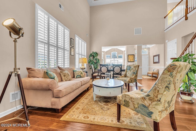 living room with a towering ceiling, hardwood / wood-style flooring, and plenty of natural light