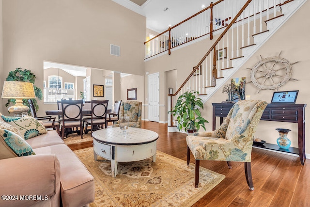 living room featuring ornamental molding, hardwood / wood-style floors, a high ceiling, and decorative columns