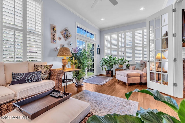 living room with crown molding, wood-type flooring, plenty of natural light, and ceiling fan