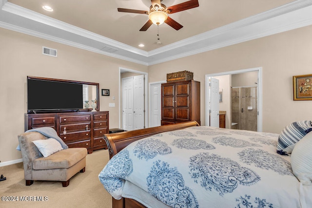 carpeted bedroom featuring ornamental molding, ensuite bath, a tray ceiling, and ceiling fan