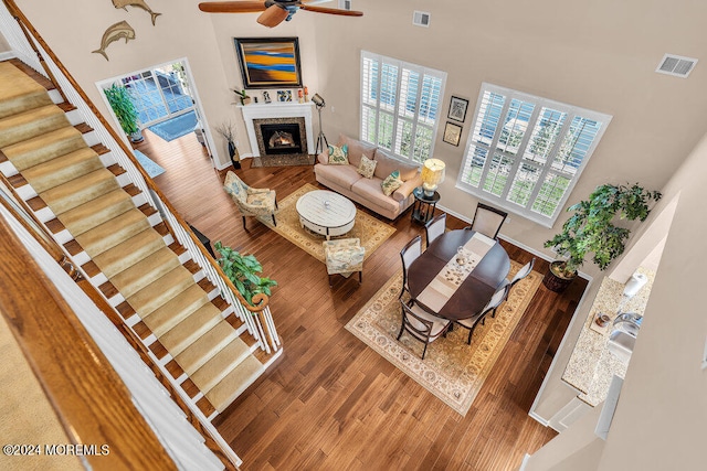 living room with a high end fireplace, wood-type flooring, and ceiling fan