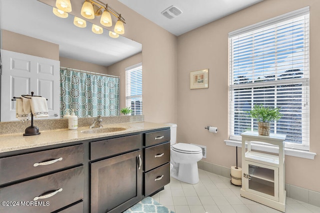 bathroom featuring a healthy amount of sunlight, vanity, toilet, and tile patterned flooring