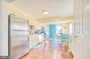 kitchen featuring hardwood / wood-style flooring, stainless steel fridge, and white cabinetry