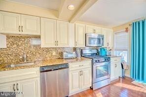 kitchen featuring stainless steel appliances, backsplash, sink, and light hardwood / wood-style flooring