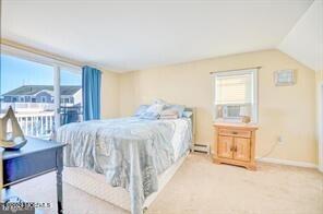 bedroom with light carpet, cooling unit, a baseboard radiator, and vaulted ceiling