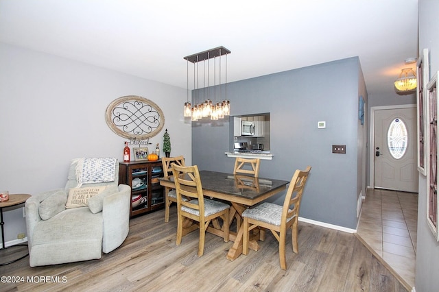 dining area with a notable chandelier and light hardwood / wood-style flooring