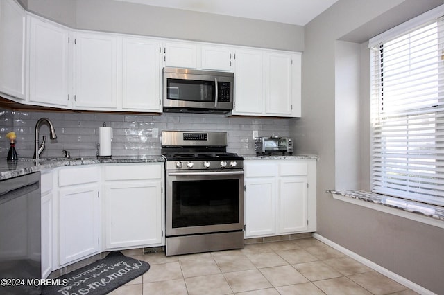 kitchen with white cabinets, appliances with stainless steel finishes, backsplash, and a wealth of natural light