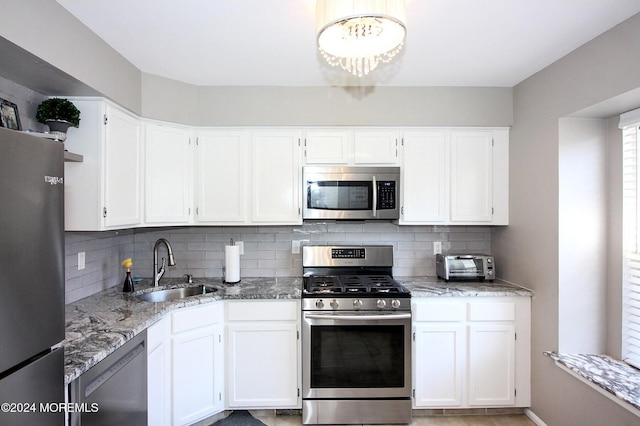 kitchen with stainless steel appliances, backsplash, sink, and white cabinetry