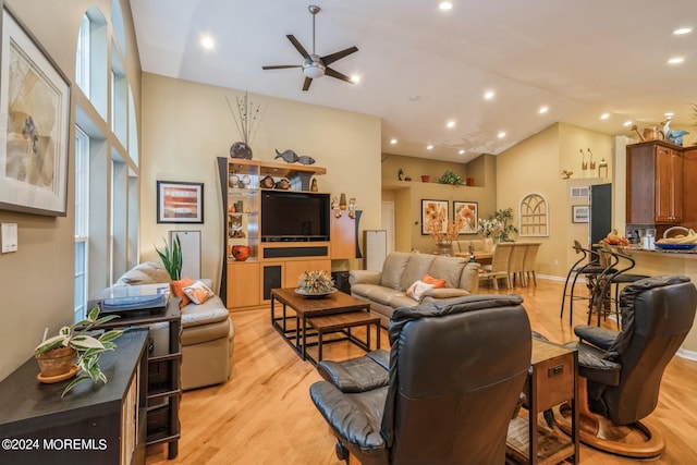 living room with ceiling fan, light hardwood / wood-style floors, and high vaulted ceiling