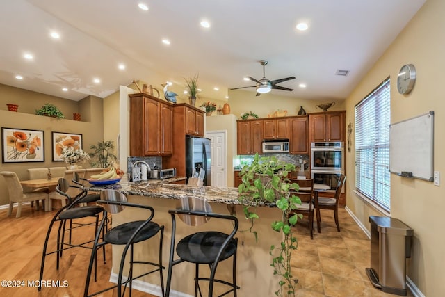 kitchen with vaulted ceiling, kitchen peninsula, backsplash, appliances with stainless steel finishes, and a kitchen bar