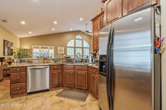 kitchen with light stone countertops, appliances with stainless steel finishes, vaulted ceiling, and kitchen peninsula