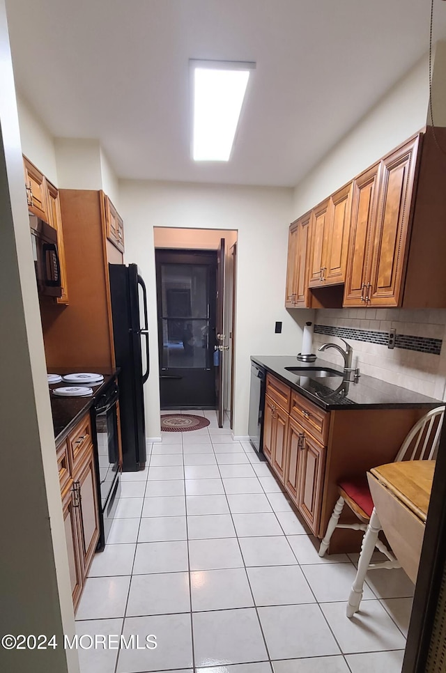 kitchen with light tile patterned flooring, black appliances, decorative backsplash, and sink