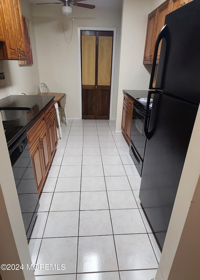 kitchen featuring dark stone countertops, light tile patterned flooring, ceiling fan, and black appliances