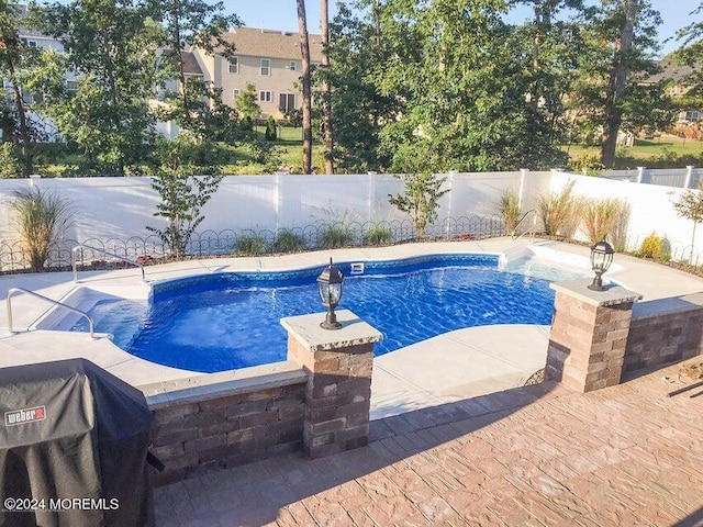 view of swimming pool featuring a jacuzzi, a grill, and a patio area