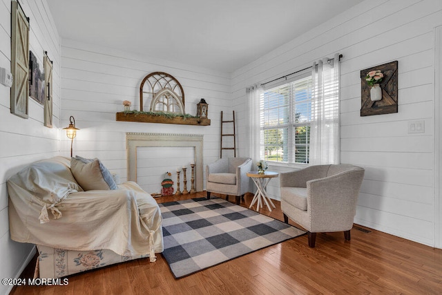 living area with hardwood / wood-style flooring and wood walls