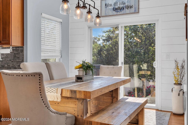 dining space featuring wooden walls and light wood-type flooring