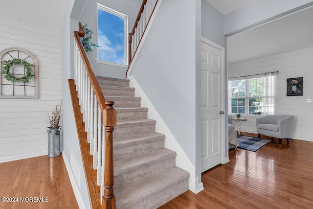 stairway with hardwood / wood-style flooring and wood walls