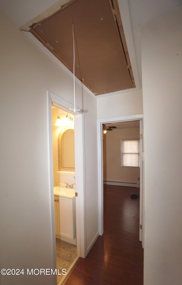 hall featuring a baseboard radiator, sink, and dark hardwood / wood-style flooring