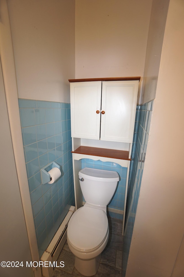 bathroom featuring tile patterned flooring, baseboard heating, toilet, and tile walls