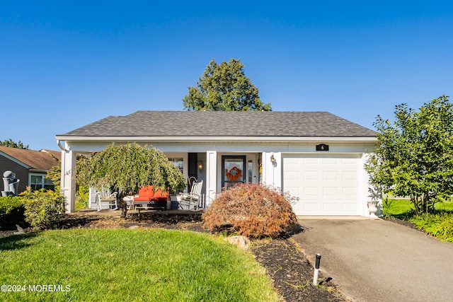 view of front of house with a porch, a front yard, and a garage