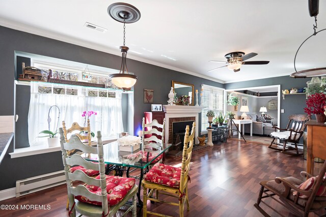 dining room with a brick fireplace, ceiling fan, dark hardwood / wood-style floors, a baseboard heating unit, and ornamental molding