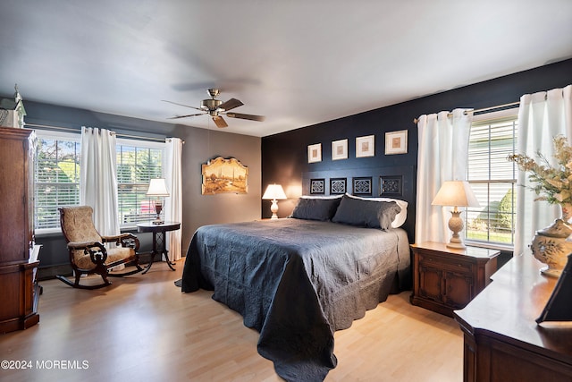 bedroom with ceiling fan, light hardwood / wood-style floors, and multiple windows