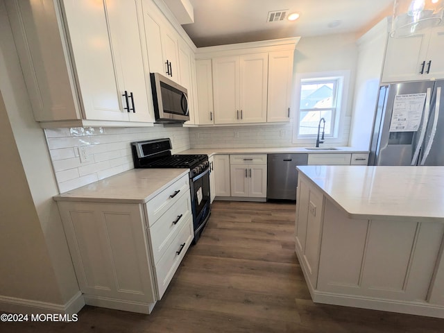 kitchen featuring stainless steel appliances, sink, decorative light fixtures, white cabinets, and dark hardwood / wood-style flooring