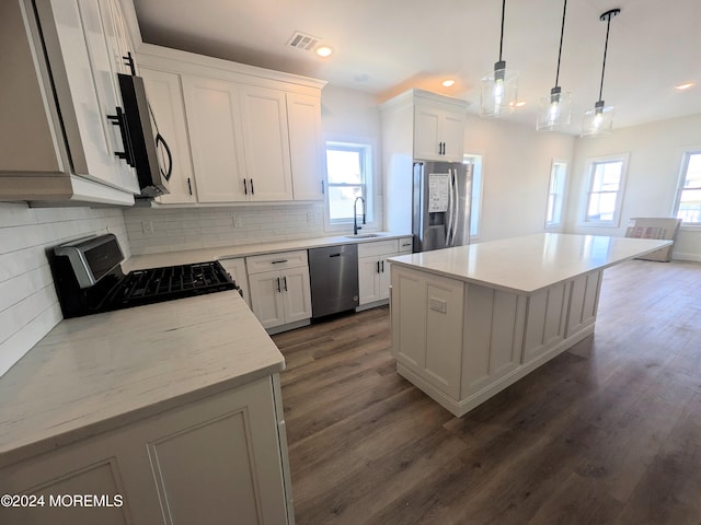 kitchen with white cabinets, a healthy amount of sunlight, stainless steel appliances, and a kitchen island