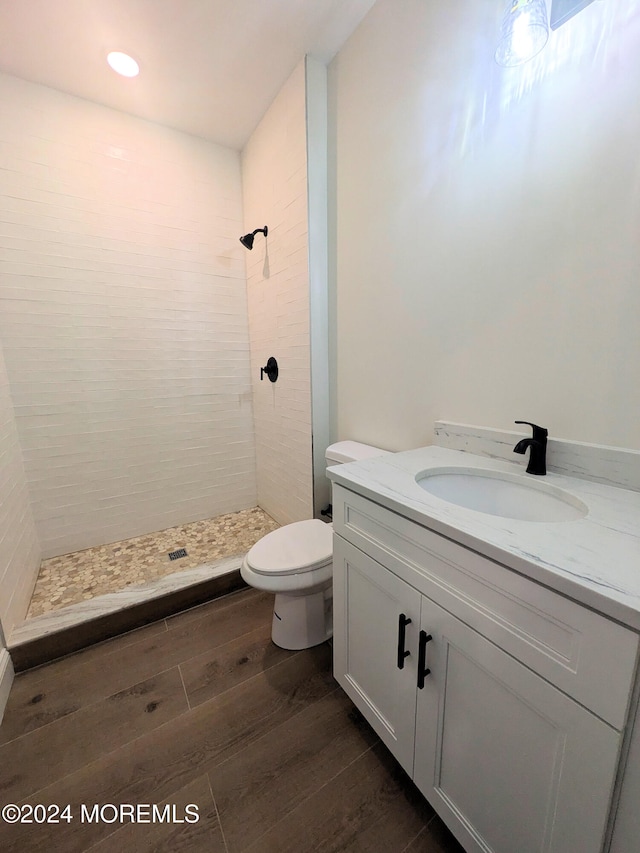 bathroom featuring vanity, toilet, hardwood / wood-style flooring, and tiled shower