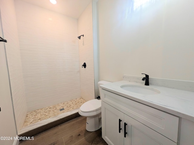 bathroom with vanity, hardwood / wood-style floors, tiled shower, and toilet