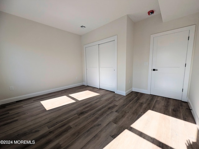 unfurnished bedroom with dark wood-type flooring and a closet