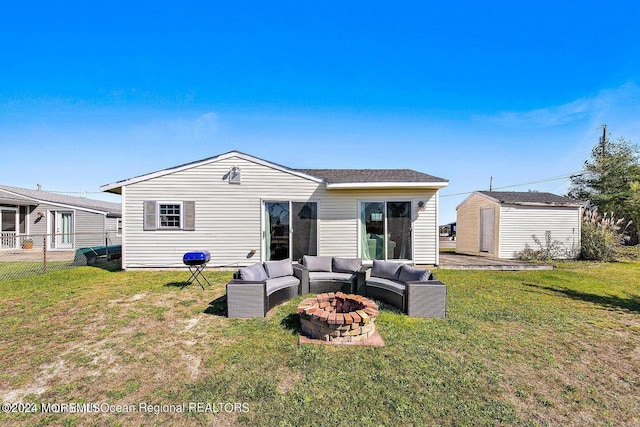 rear view of property featuring an outdoor living space with a fire pit, a yard, and a storage unit