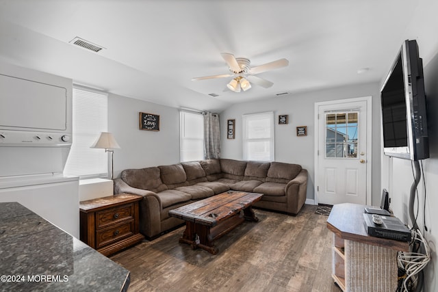 living room featuring stacked washing maching and dryer, dark wood-type flooring, vaulted ceiling, and ceiling fan