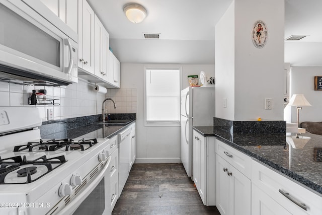 kitchen featuring white appliances, sink, white cabinetry, dark stone countertops, and dark wood-type flooring