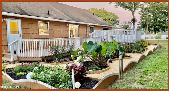 back house at dusk featuring a wooden deck