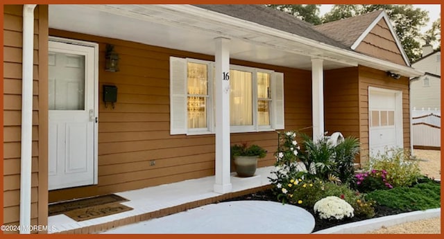 doorway to property with covered porch and a garage