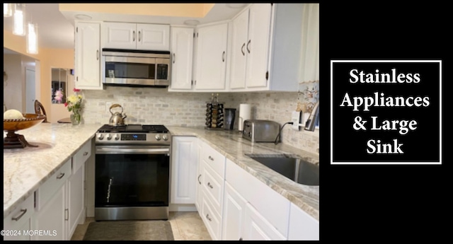 kitchen featuring sink, backsplash, stainless steel appliances, white cabinets, and light stone counters