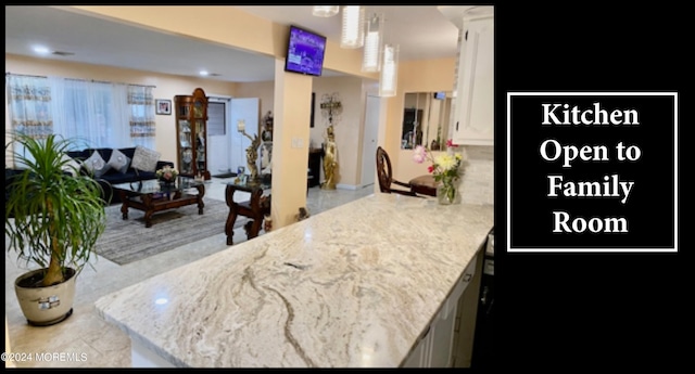 kitchen featuring kitchen peninsula, white cabinetry, and light stone counters