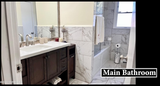 bathroom with vanity, washtub / shower combination, and tile walls