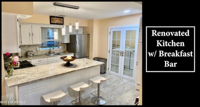 kitchen featuring tasteful backsplash, sink, french doors, white cabinets, and stainless steel refrigerator