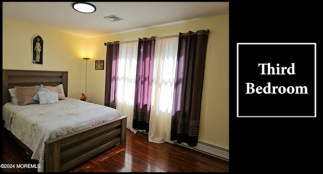 bedroom featuring a baseboard heating unit and dark hardwood / wood-style floors