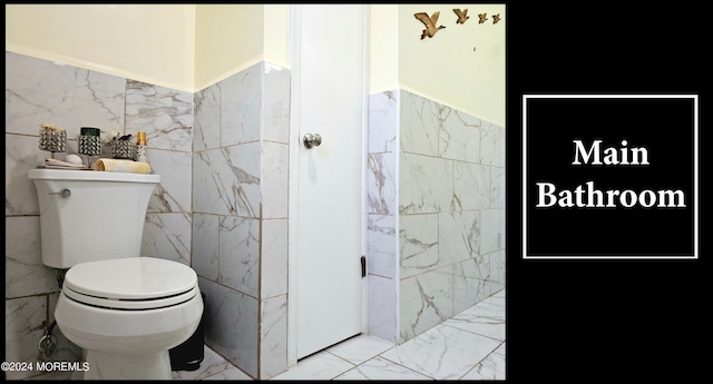 bathroom featuring toilet and tile walls