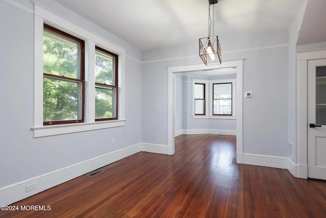 unfurnished dining area with crown molding, an inviting chandelier, and dark hardwood / wood-style floors