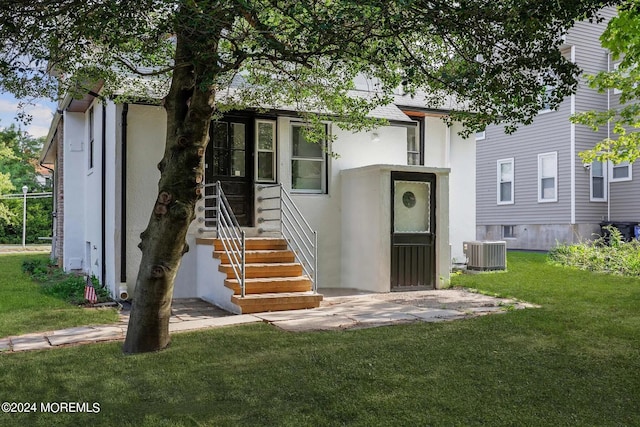 view of front facade with a front yard and central AC unit