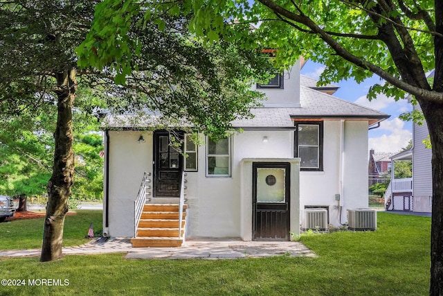 view of front of home featuring cooling unit and a front yard