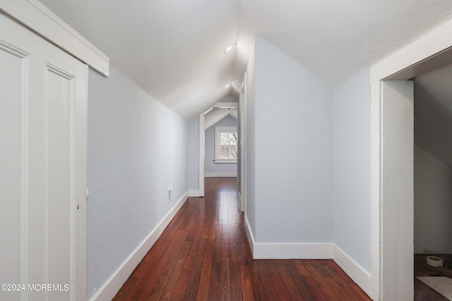 hallway with vaulted ceiling and dark hardwood / wood-style flooring